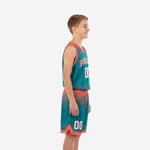 Left side view of youth sublimated basketball uniforms showing orange V-neck binding, armhole trim, and halftone dot pattern on teal jersey and shorts
