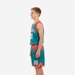 Right side view of teal and orange custom youth basketball uniform set showing shorts hem notch and full halftone sublimated pattern